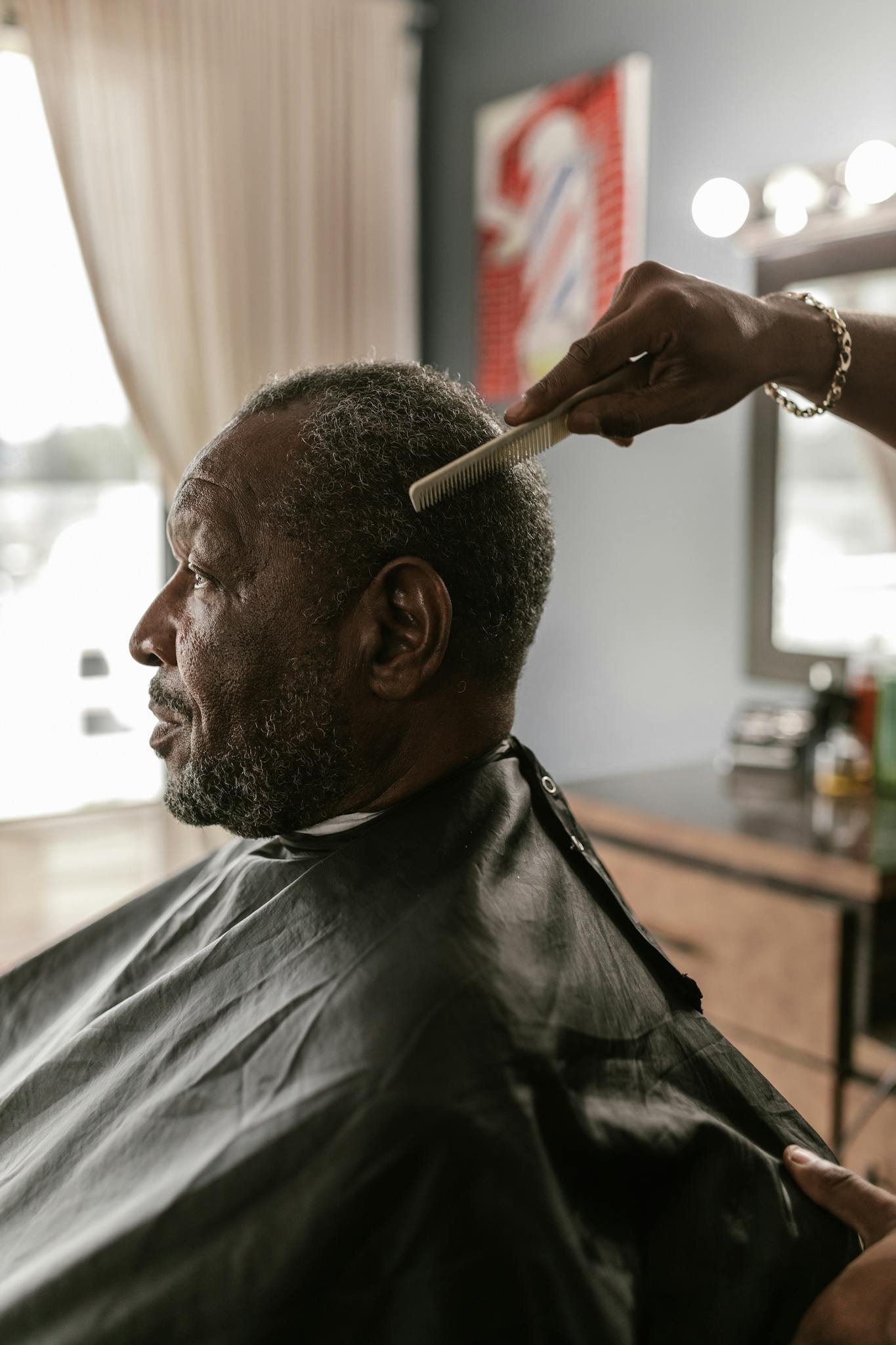 Close-up of a senior man receiving a haircut in a stylish barber shop.
